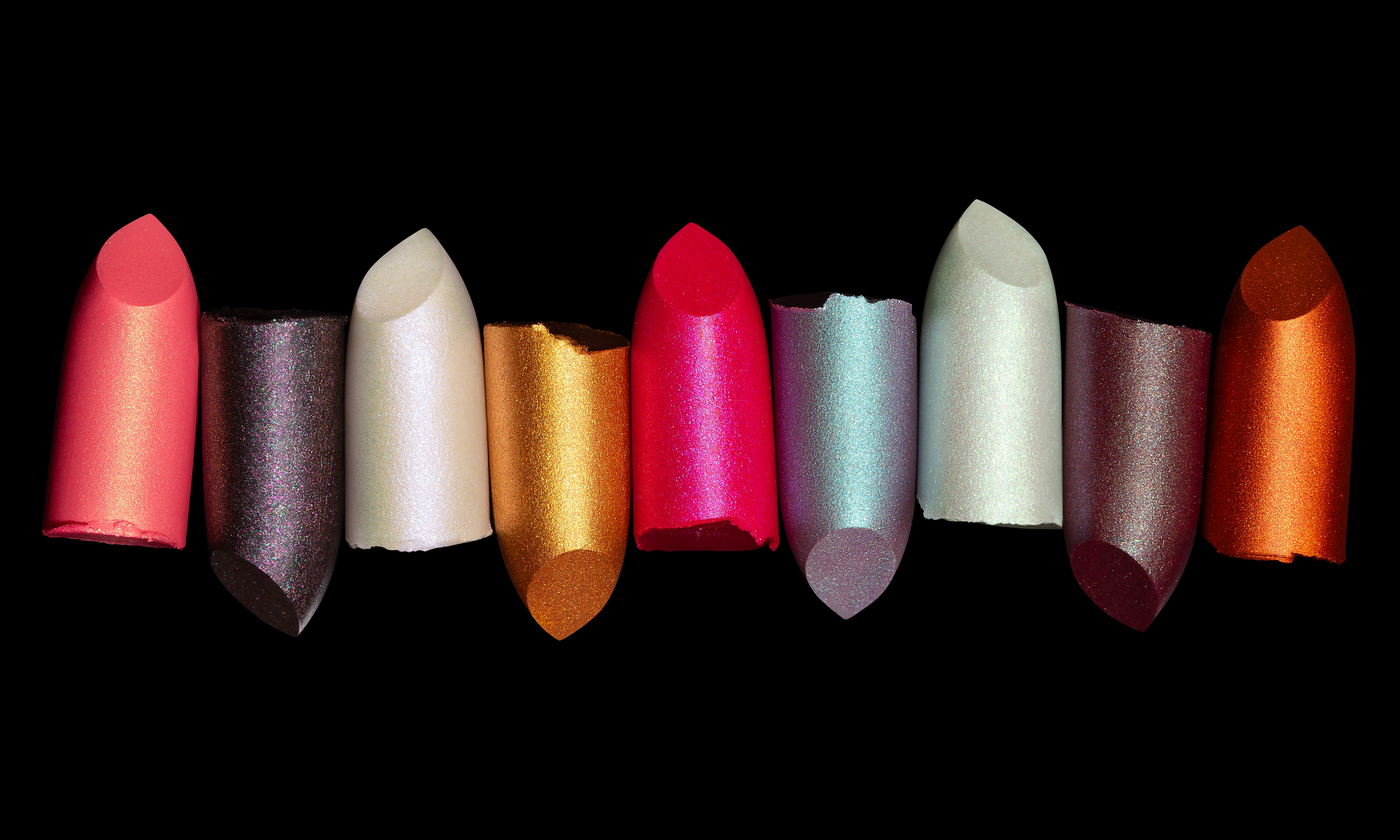 Row of colorful goth editorial lipstick shades on a black background