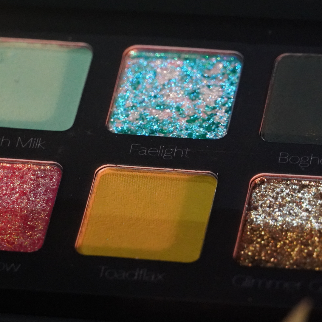 Close-up of a makeup palette with glittery and colorful shades.